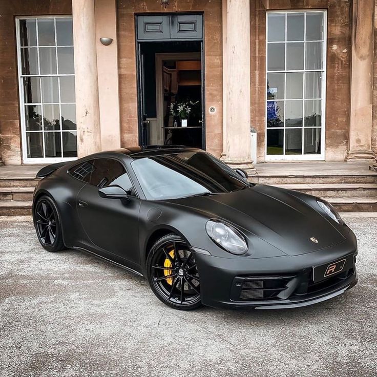 a black sports car parked in front of a building with steps leading up to it