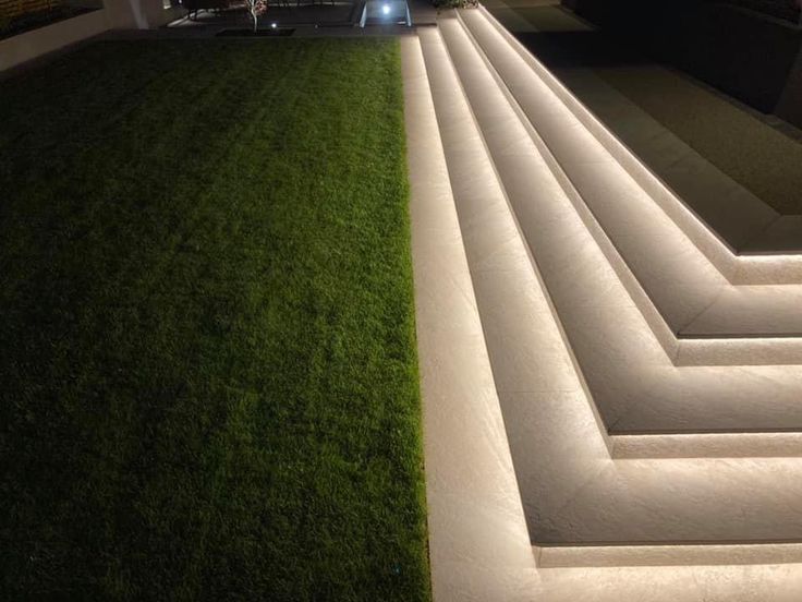 an outdoor area with grass and steps lit up at night