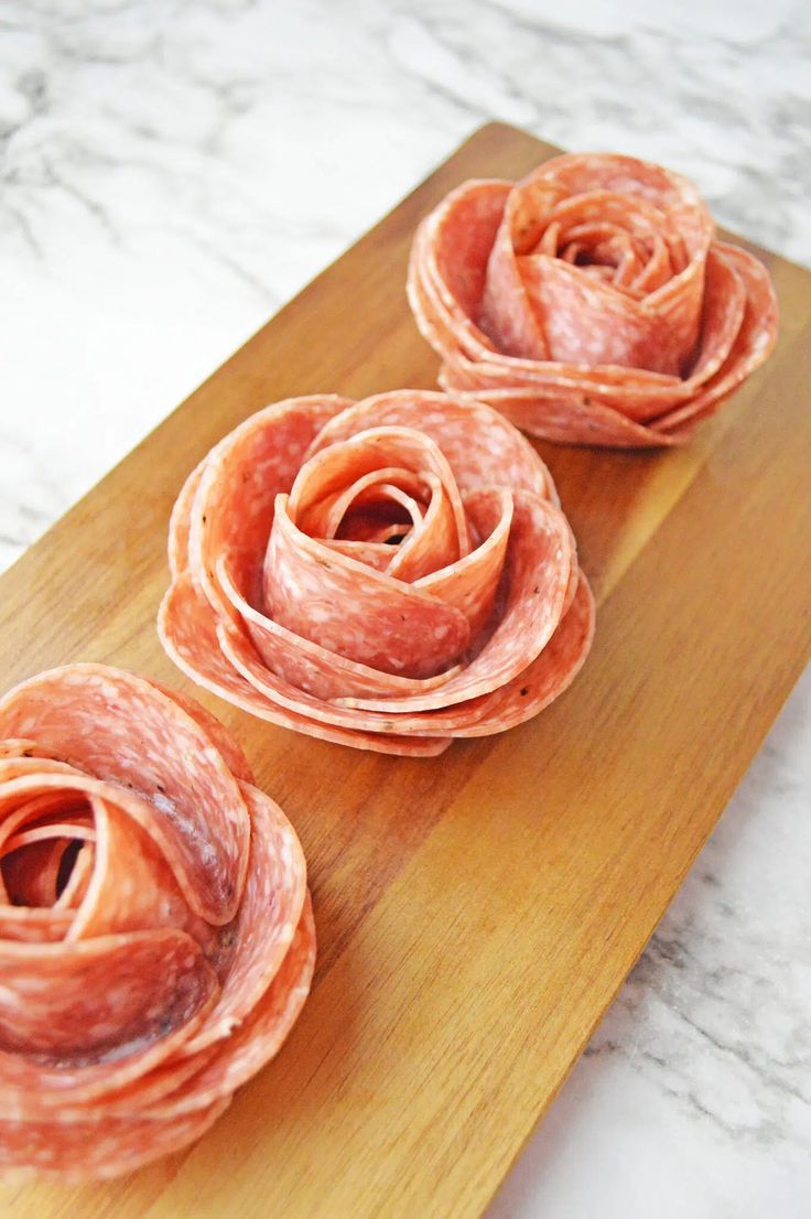 three slices of ham sitting on top of a wooden cutting board