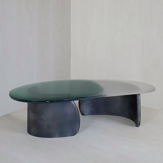 an oval glass table sitting on top of a white floor next to a wooden wall