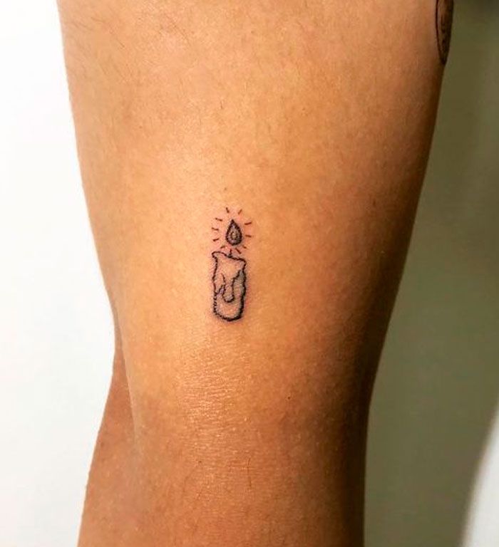 a person with a small tattoo on their leg that has a lit candle in it