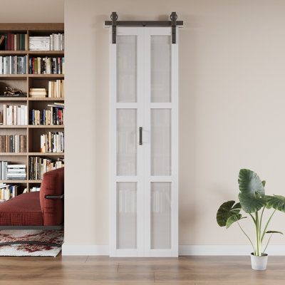 a living room filled with furniture and a tall book case next to a plant on the floor