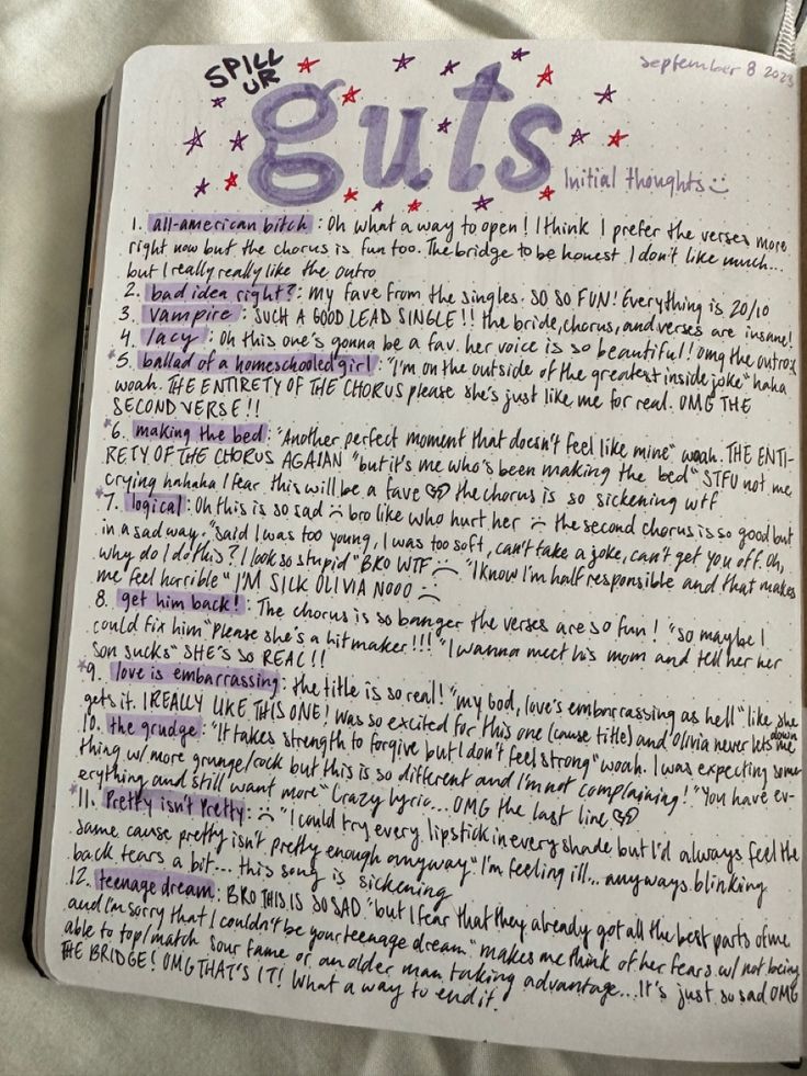 an open notebook with the words guts written in purple and blue ink on top of it