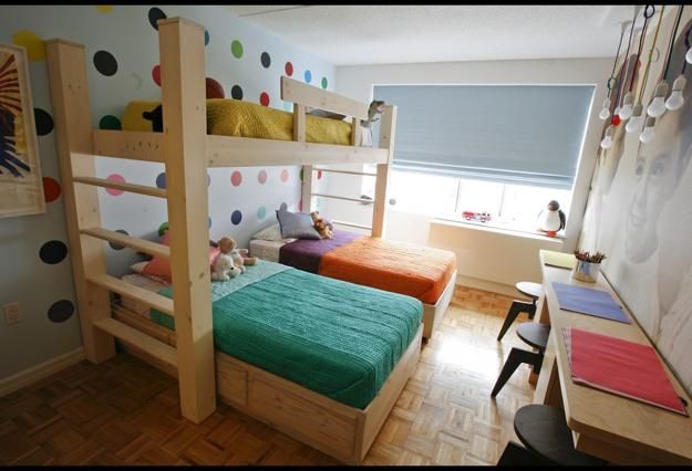 a bedroom with bunk beds and desks in the corner, along with other furniture