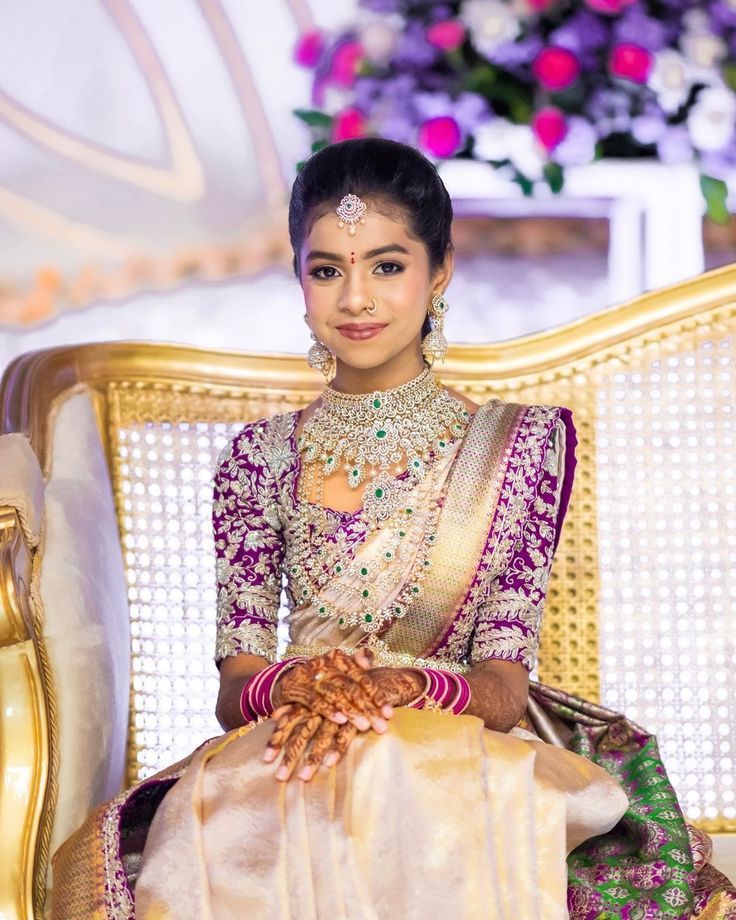 a woman sitting on top of a chair wearing a bridal dress and jewelry in her hand