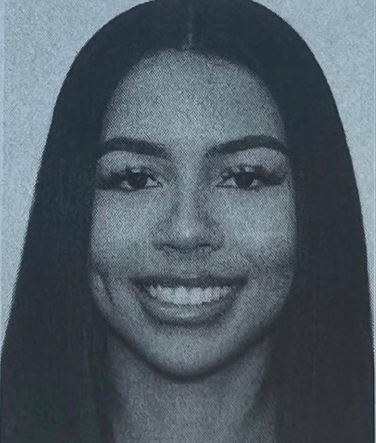 a black and white photo of a woman with long dark hair smiling at the camera