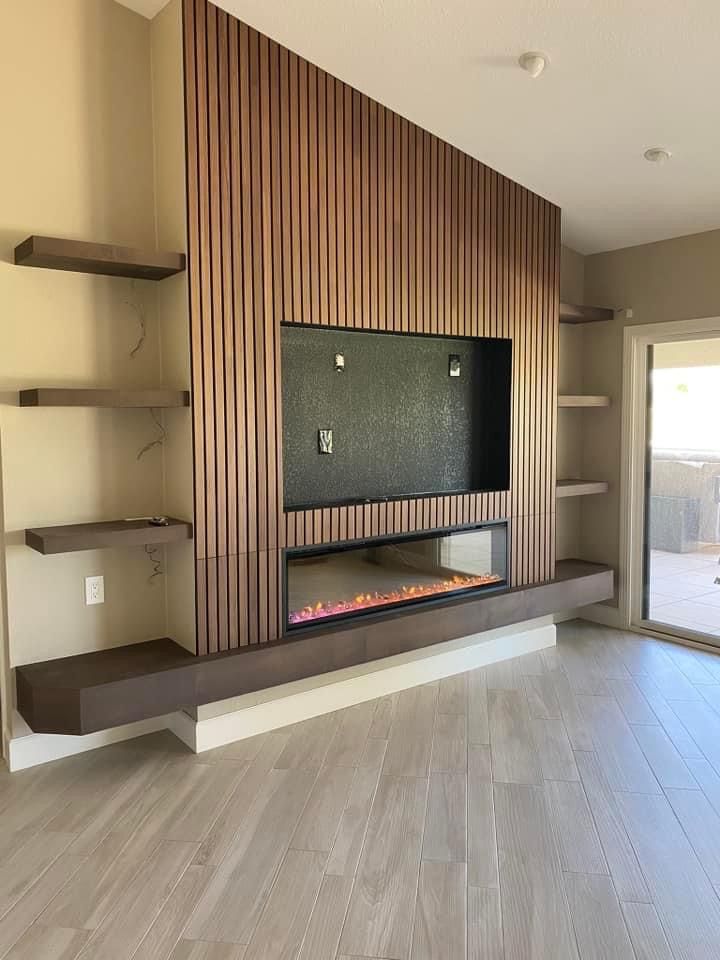 an empty living room with a fireplace in the center and open shelves on either side