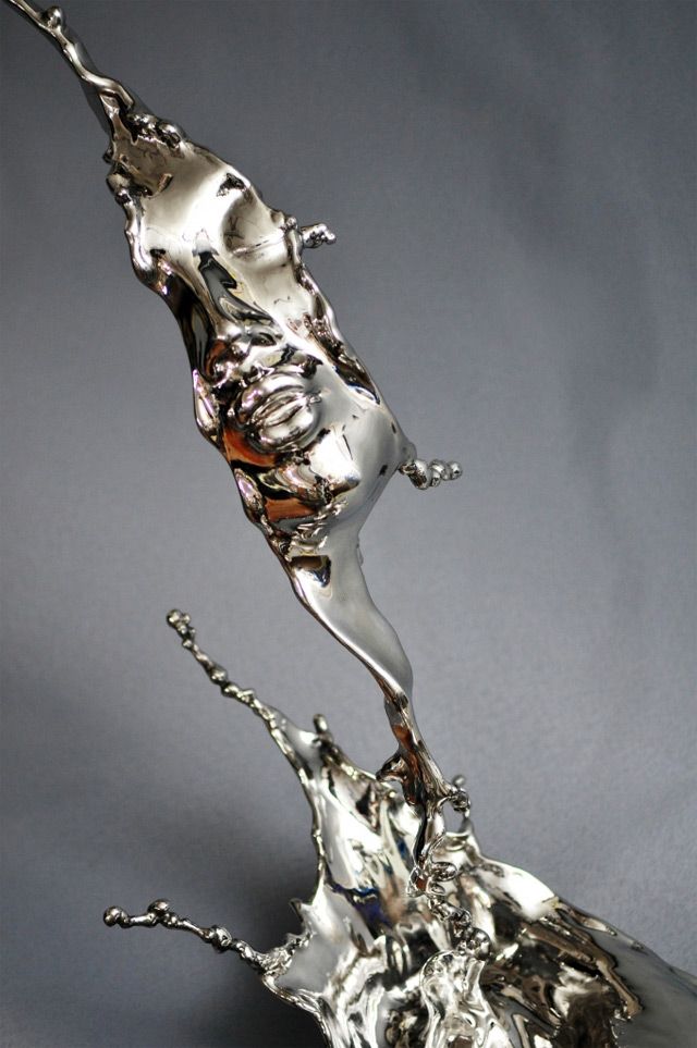 a silver object with water splashing out of it