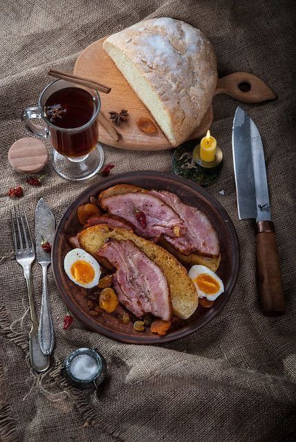 a plate with meat, eggs and bread on it next to some utensils