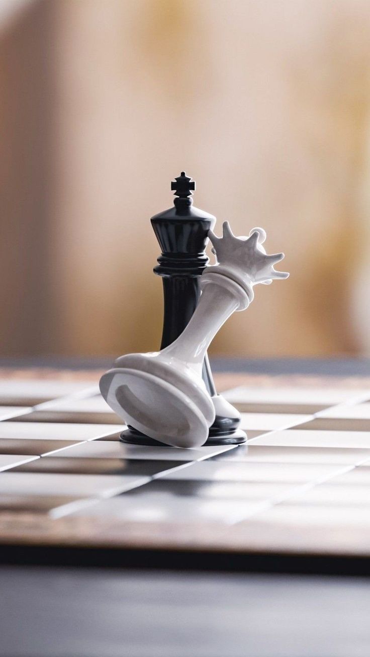 a black and white chess piece sitting on top of a checkerboard board with the queen in focus