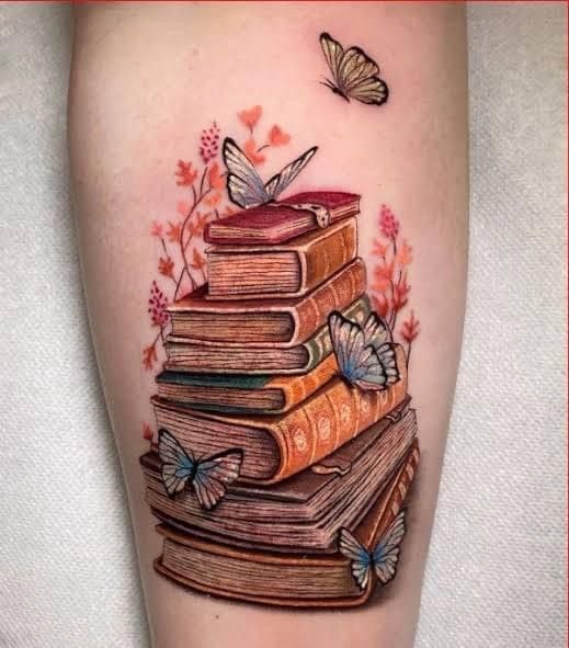 a tattoo with books and butterflies on the thigh, as well as a butterfly flying over them