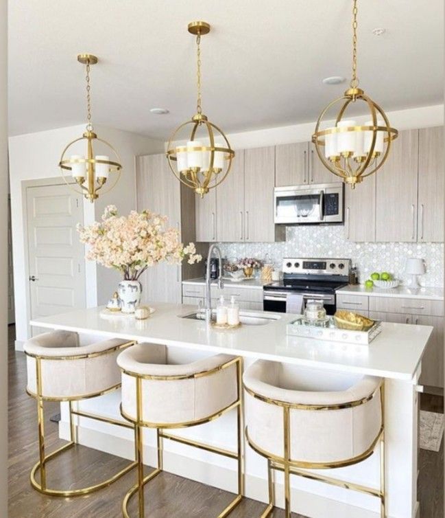 a kitchen with white counter tops and gold accents