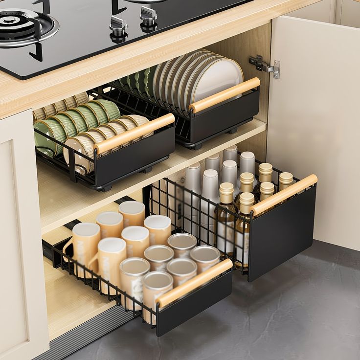 an open cabinet with dishes and pans in the bottom drawer, next to a stove