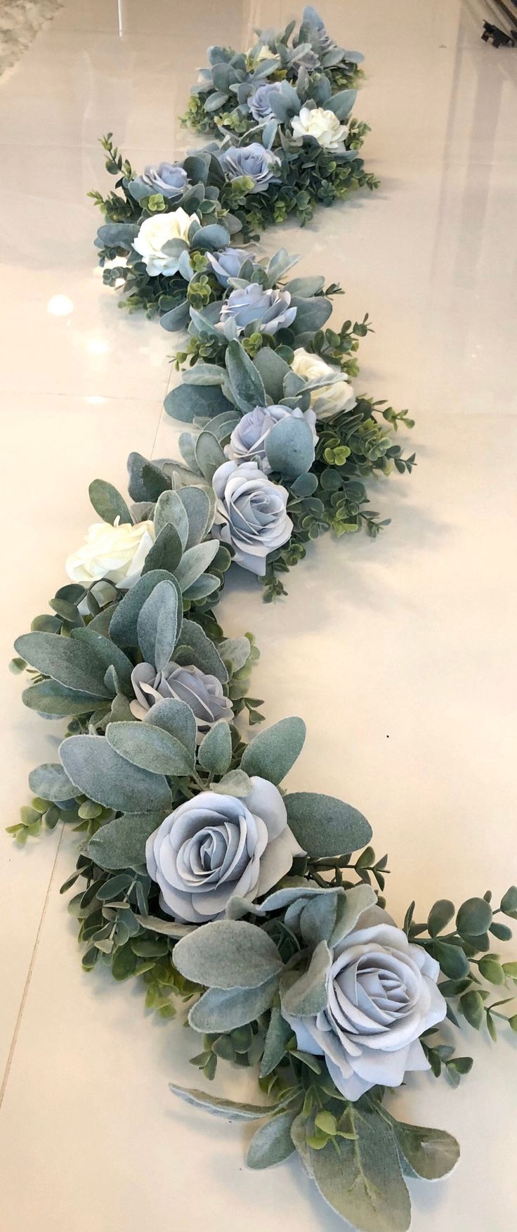 the flowers are lined up on the floor to be arranged in a long line with greenery