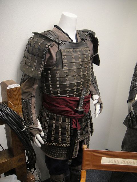 a mannequin dressed in armor is standing next to a chair