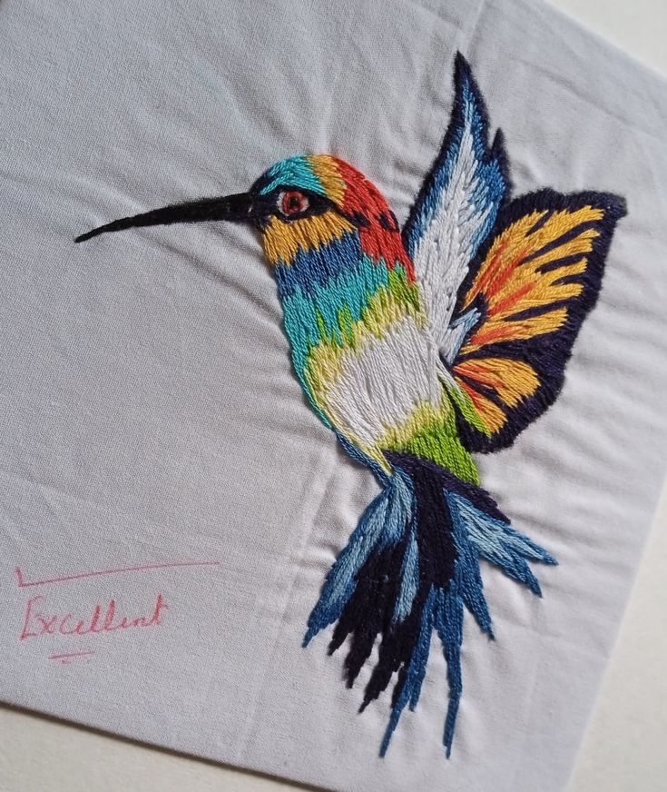 a colorful bird embroidered onto a white piece of cloth