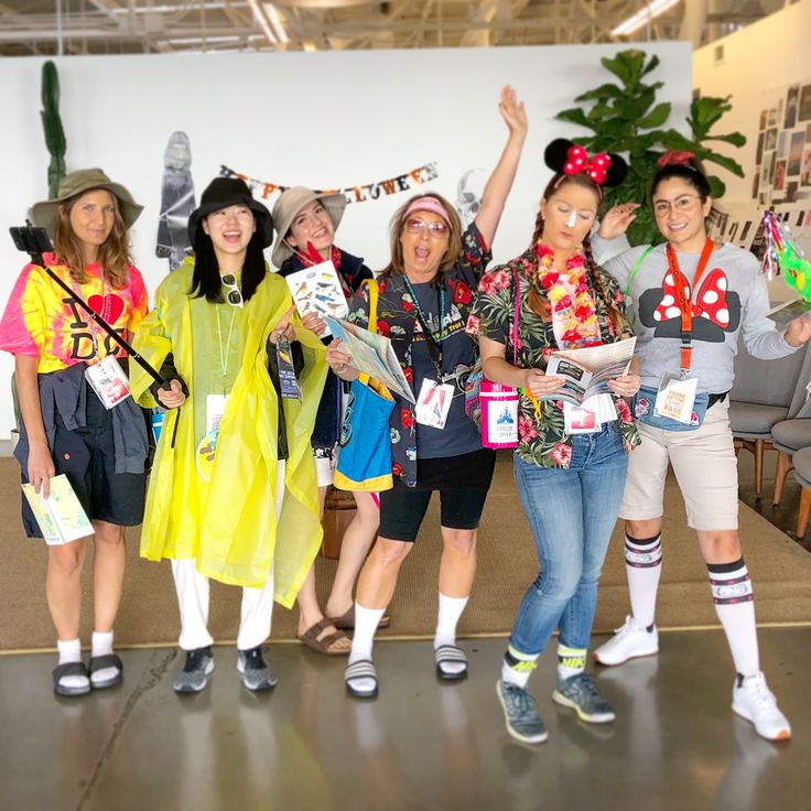 several women dressed up in costumes posing for the camera with their arms in the air