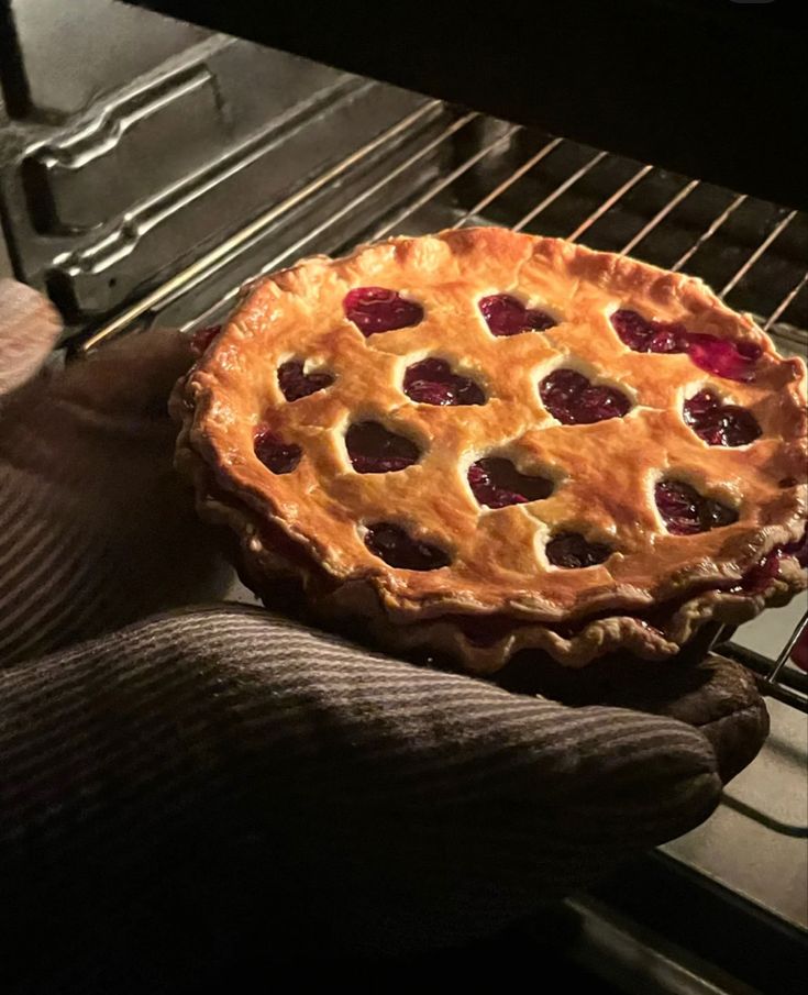 a pie sitting on top of an oven with someone's hand holding it up