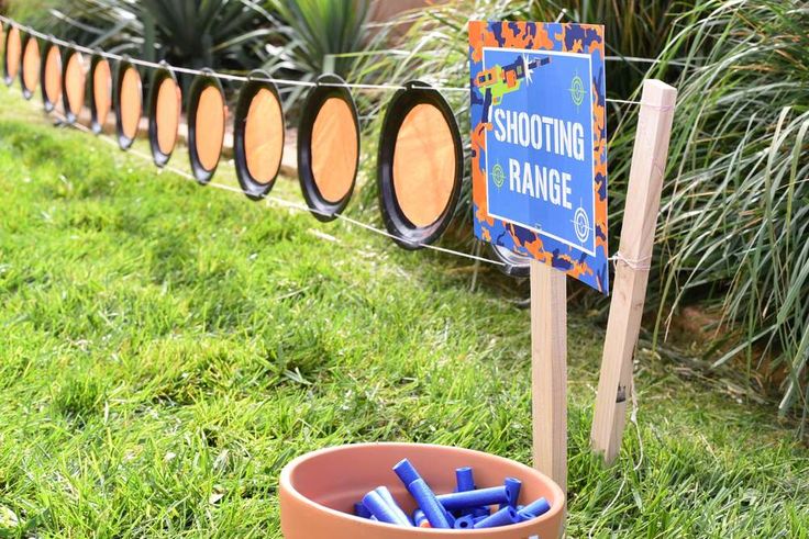 there is a sign that says shooting range in front of some barrels with markers on them