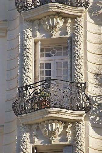 an ornate balcony and balconies on the side of a white building with wrought iron railings