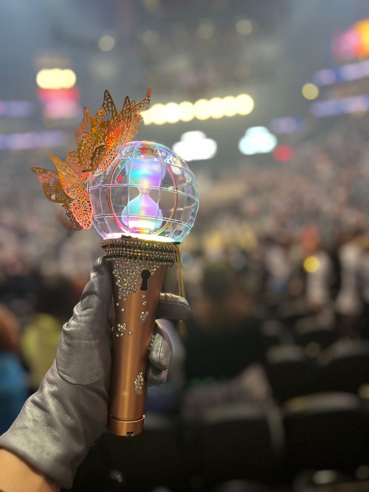 a person holding up a crystal ball in front of a crowd at a sporting event