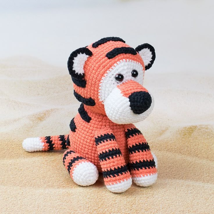 a crocheted stuffed animal sitting on top of sand