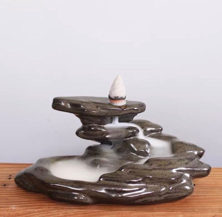 a small fountain made out of rocks on top of a wooden table