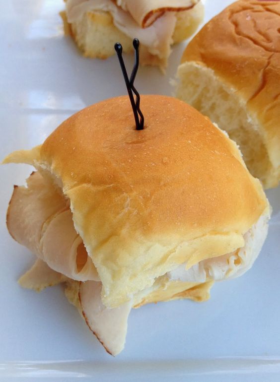 two ham and cheese sliders on a plate with toothpicks in the middle