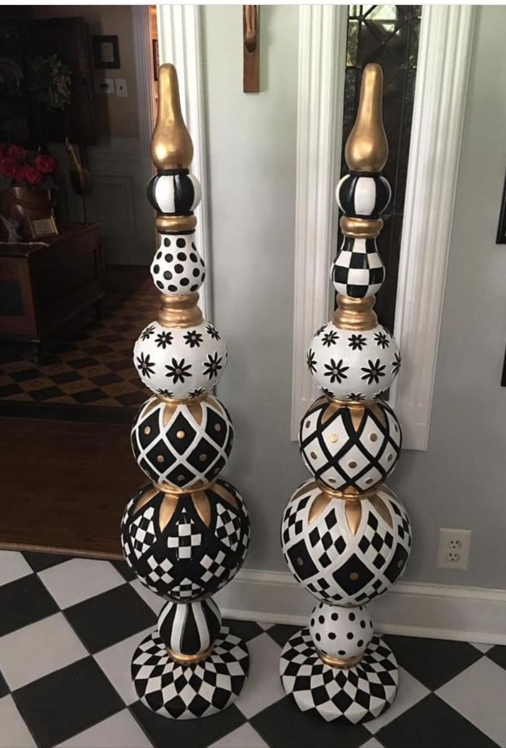 two black and white vases sitting on top of a checkered floor