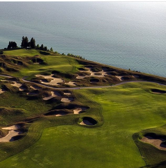 an aerial view of a golf course with water in the background