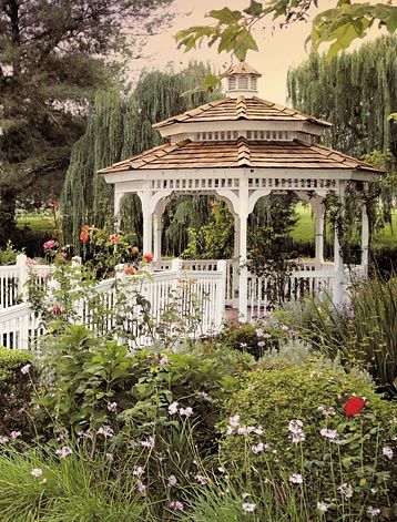 a white gazebo surrounded by flowers and trees