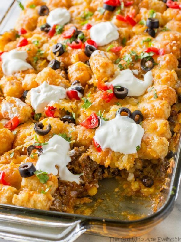 a casserole dish with meat, cheese and olives on top is shown