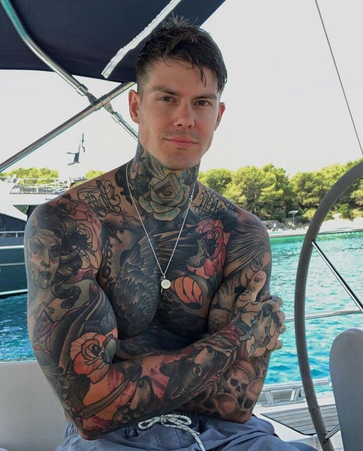 a man with tattoos sitting on a boat