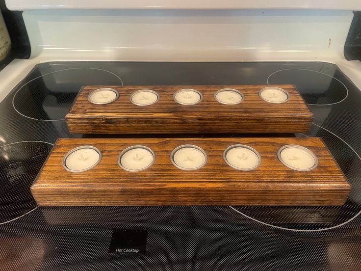 two wooden trays filled with candles sitting on top of an electric stove burners