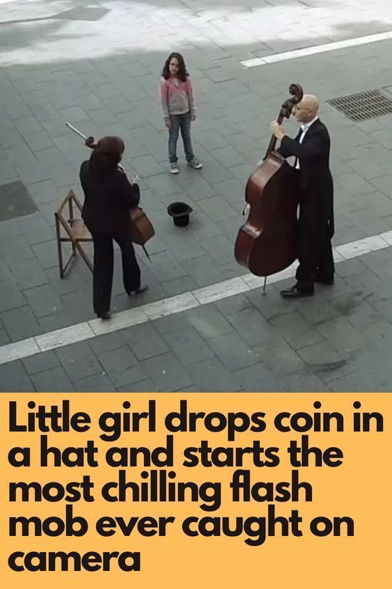 three people are standing on the sidewalk playing instruments and one person is holding a camera