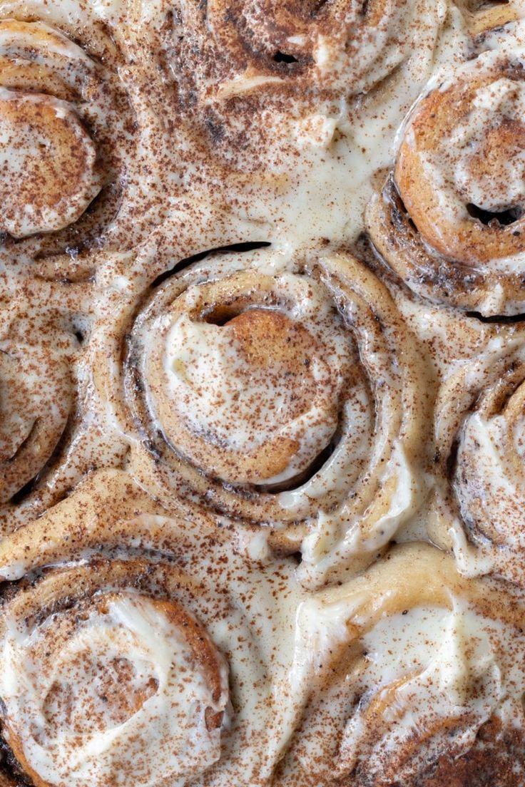 cinnamon rolls covered in powdered sugar on top of a pan filled with icing