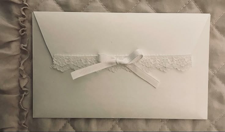 an envelope with a white ribbon and lace on it