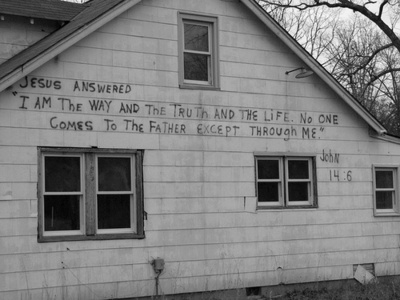 an old white house with writing on the side and windows that says jesus answered i am the way and thru the life no one comes to the father except through me