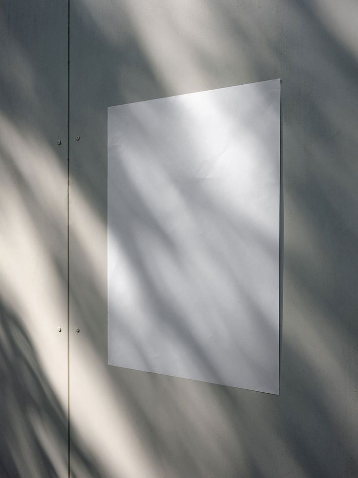 a white piece of paper hanging on the side of a wall with shadow from it