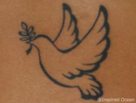 a bird with an olive branch in it's beak is shown on the back of a woman's stomach