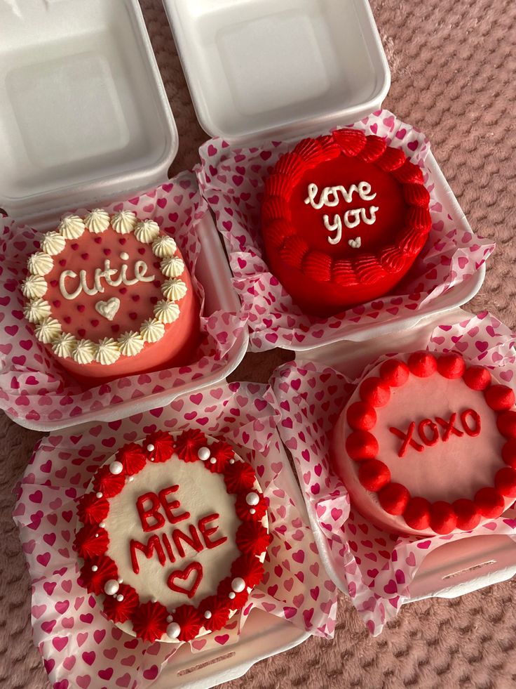 four valentine's day cakes in plastic containers on a table