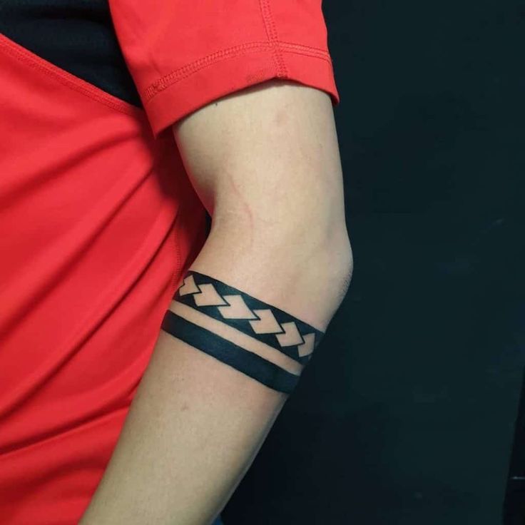 a person wearing a red shirt with a black and white tattoo on their arm,