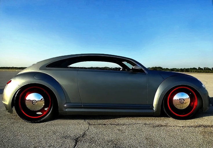 a gray car with red rims parked in a parking lot next to a blue sky