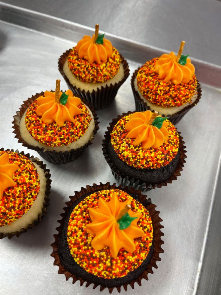 six cupcakes decorated with orange and yellow sprinkles