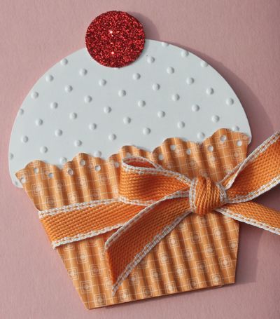 an orange and white cupcake with a red polka dot on it's top