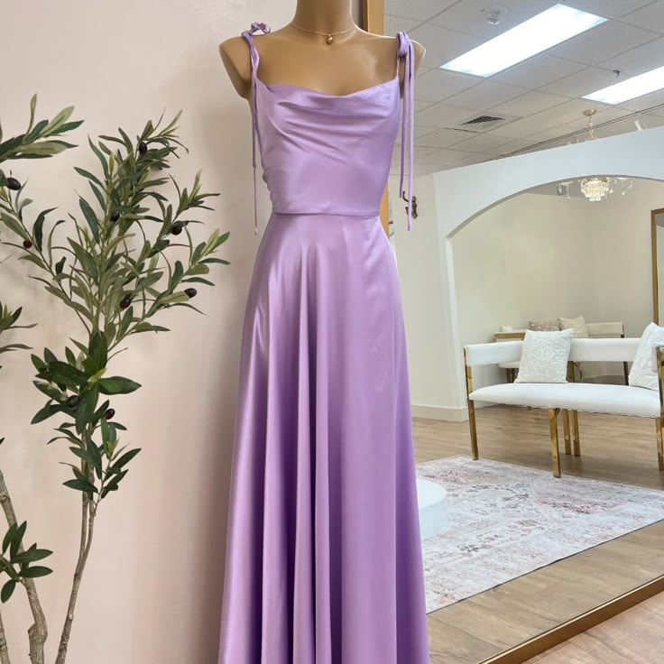 a dress on display in front of a mirror with a plant next to the window