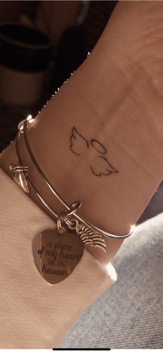 a woman's arm with two bracelets and a heart shaped charm on it