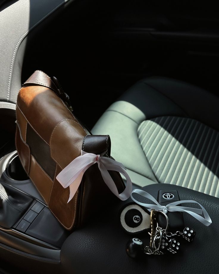 a brown purse sitting on top of a car seat next to a pair of keys