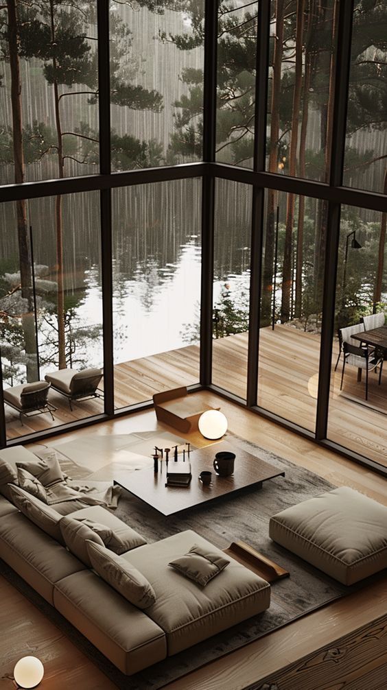 a living room filled with lots of furniture next to a large glass window overlooking a lake