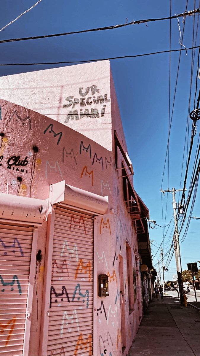 a pink building with graffiti on it and power lines in the background